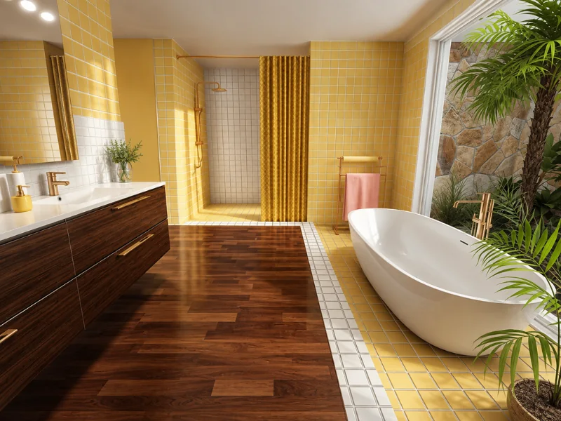 Bright yellow bathroom with a freestanding white tub, dark wood vanity, walk-in shower, warm wood flooring, tropical plants, and gold fixtures.