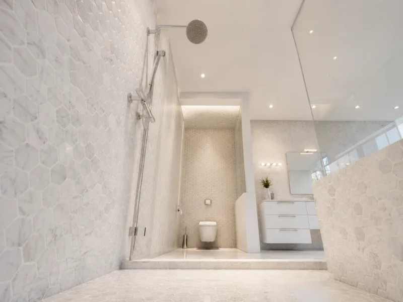White marble bathroom with a walk-in shower, wall-mounted toilet, floating vanity, and hexagon tile walls.