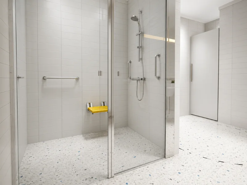 Accessible walk-in shower with glass doors, grab bars, handheld showerhead, and a folding yellow seat.