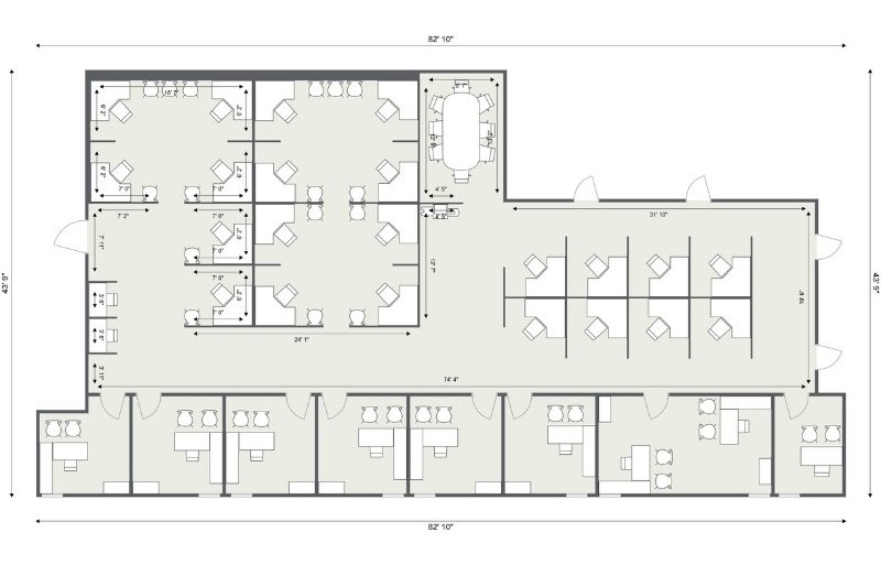 2D office floor plan with labeled measurements showing a large open workspace, several cubicle zones, private offices, and a conference room. The layout includes individual desks, meeting areas, and workstations arranged for efficient flow within the rectangular floor plan.