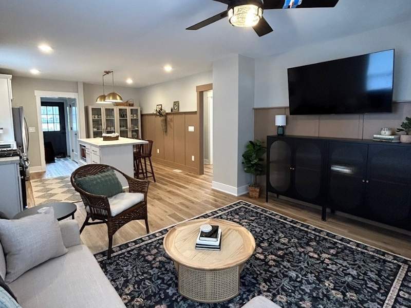 Inviting open-concept living room and kitchen with wood floors, a cozy sofa, and a large wall-mounted TV.