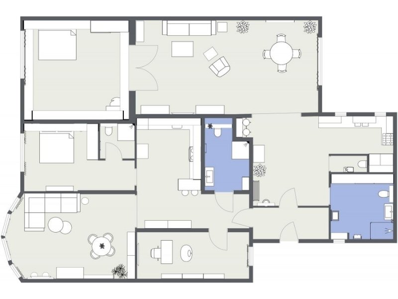 2D floor plan of a one-bedroom duplex apartment with multiple living areas. The layout includes a large living room, a dining area, a kitchen, one bedroom, two bathrooms, and additional multipurpose rooms. Furniture placement is shown, with blue highlighting the bathroom and laundry areas.