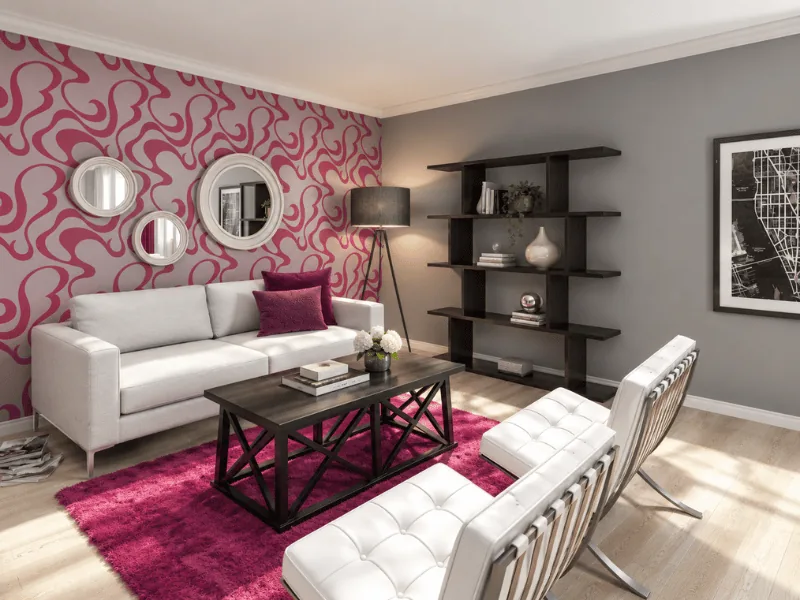 Small living room with a pink patterned feature wall, white sofa, black shelving, and a bright rug.