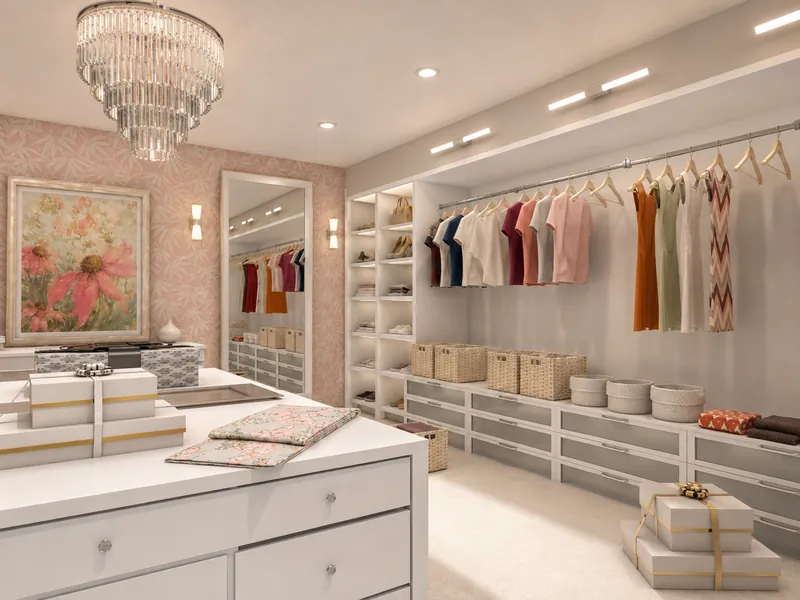 Elegant walk-in closet with white built-in drawers and shelving, neatly arranged clothing, woven storage baskets, a central island, floral wallpaper and artwork, a full-length mirror, and a tiered crystal chandelier.