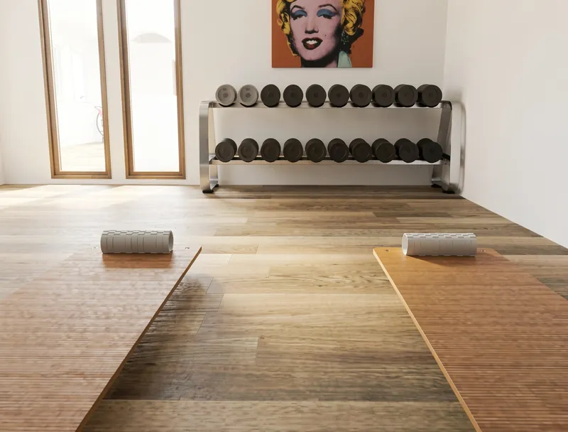 Home gym with two exercise mats and foam rollers facing a two-tier dumbbell rack, beneath a colorful pop-art portrait.