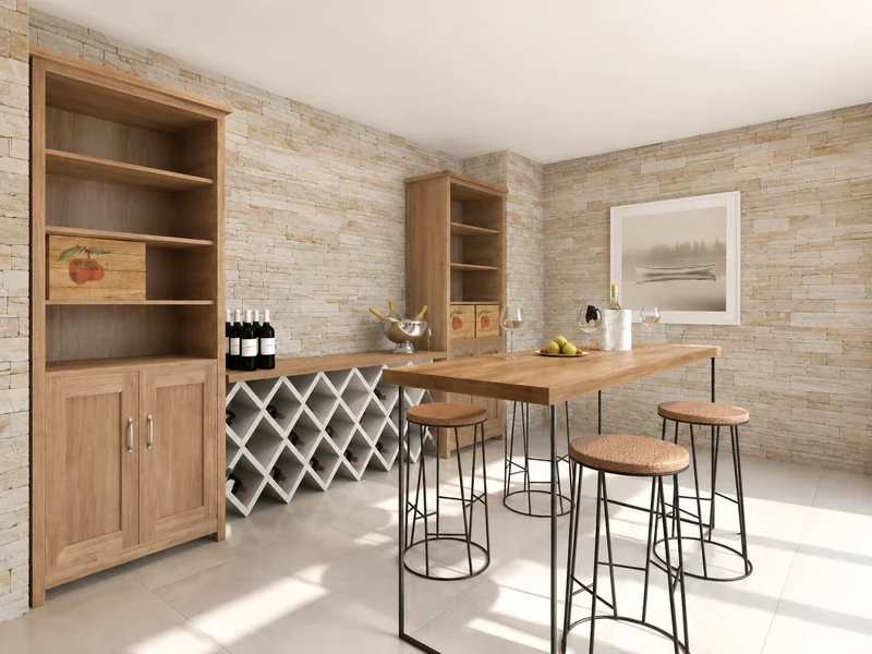 Wine-tasting room with stone walls, wooden shelving, a built-in wine rack, a high wooden table with four stools, wine bottles, glasses, and an ice bucket.