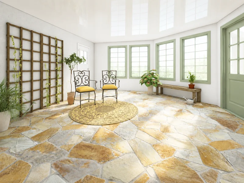 Sunlit conservatory with stone flooring, two wrought-iron chairs on a round rug, climbing plants on a wooden trellis, potted greenery, and pale green framed windows and doors.