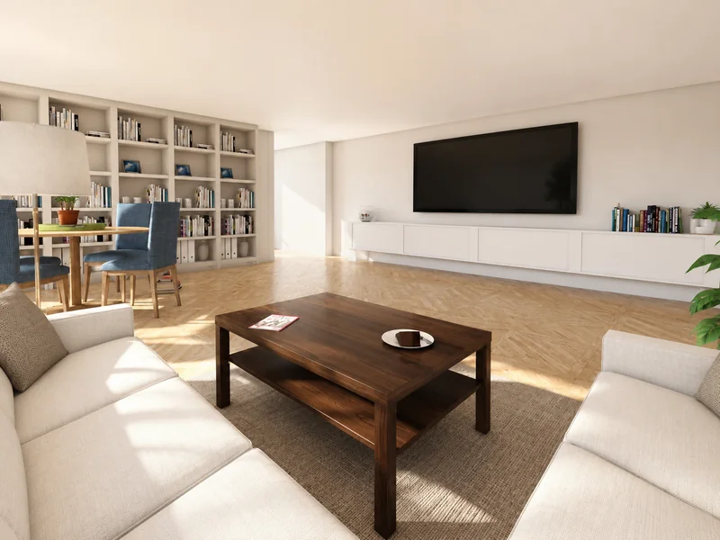 Bright modern living room with white sofas, a dark wood coffee table, a large wall-mounted TV above low cabinetry, built-in bookshelves, and a dining area with blue chairs.