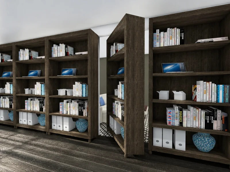 Library with rows of dark wood bookcases filled with books, storage boxes, decorative blue vases, and small display screens, forming narrow passageways.