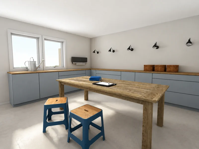 Bright workshop or craft room with a large wooden worktable, two blue stools, gray built-in cabinets, wicker baskets, wall-mounted task lights, and two windows.