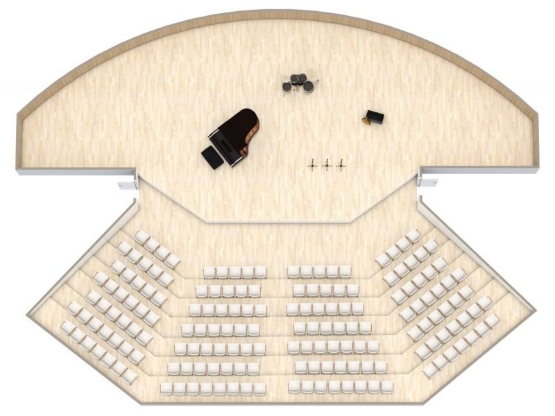 Floor plan of a concert hall with a curved stage area featuring a grand piano, drum set, and microphones. The audience seating is arranged in angled rows facing the stage, with wide aisles for easy access. The space has light wooden flooring throughout.