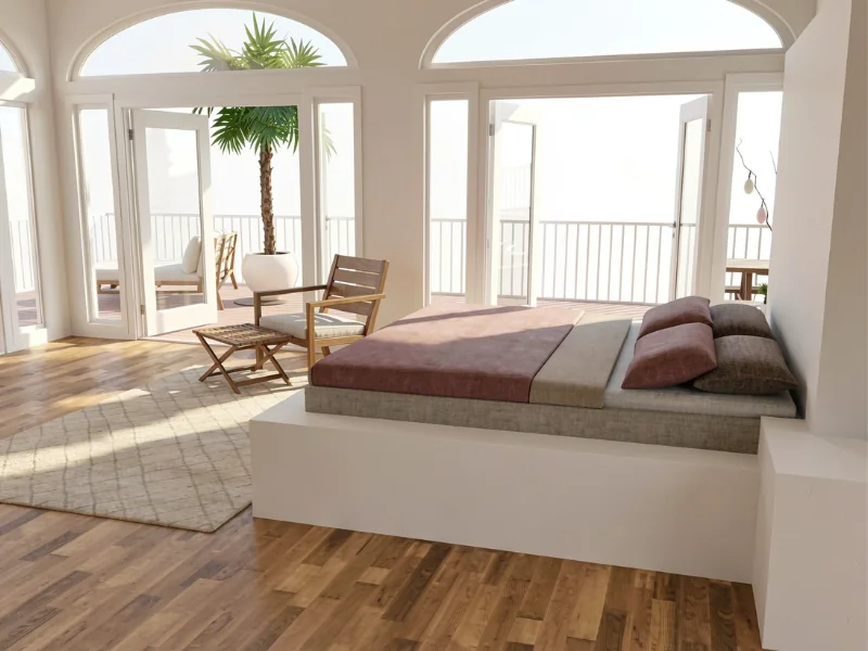 Bright modern bedroom with a built-in platform bed, neutral bedding, and mauve accents. Floor-to-ceiling glass doors and arched windows open to a balcony, while a wooden lounge chair, footstool, large potted palm, area rug, and warm wood flooring complete the airy space.