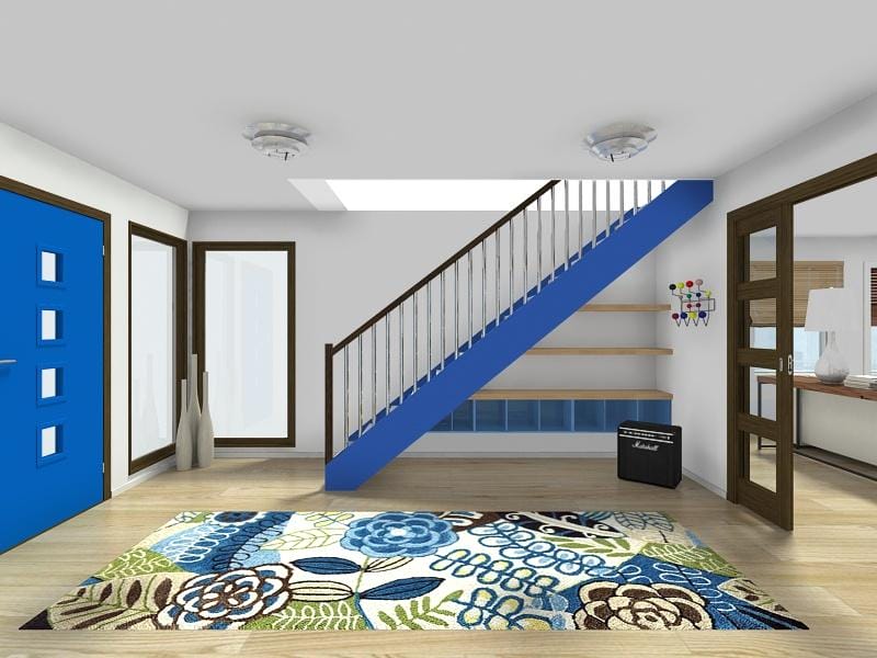 3D interior rendering of a modern entryway featuring a bright blue front door, floral patterned area rug in blue and green tones, and a staircase with a blue base and wooden steps. Under the stairs are open shelves and a storage unit, alongside a small black Marshall amplifier. The space includes large windows, wood-framed glass doors, and a skylight for natural light.