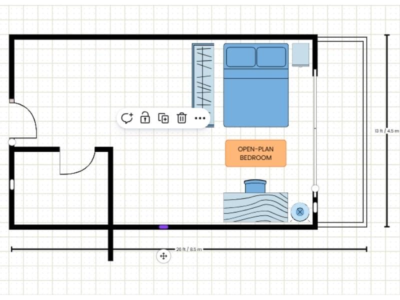 2D floor plan made with a template in Canva. It shows how to edit in the template. The floor plan is illustrating the difficulty of extending one room. The long wall was extended and the smaller room had one wall extended, however after the long wall was pushed back up, the walls were not connected. The floor plan shows a two-room floor plan with a balcony and blue furniture such as a double bed, a closet, a nightstand, a desk with a chair and a lamp. There is also an orange label saying "open-plan bedroom". There are measurements showing the size of the floor plan outside the walls of the floor plan.