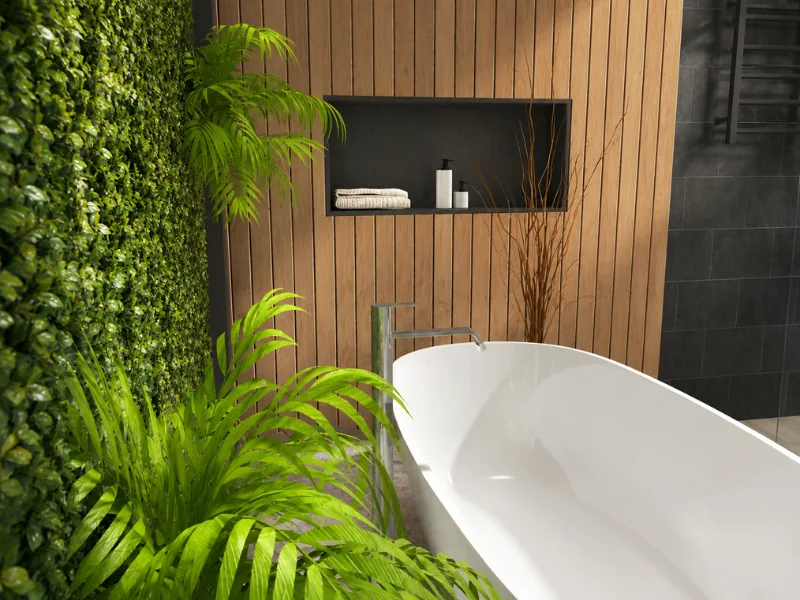 Modern spa bathroom with a white freestanding tub, vertical wood paneling, a recessed shelf, lush tropical plants, and a green living wall.