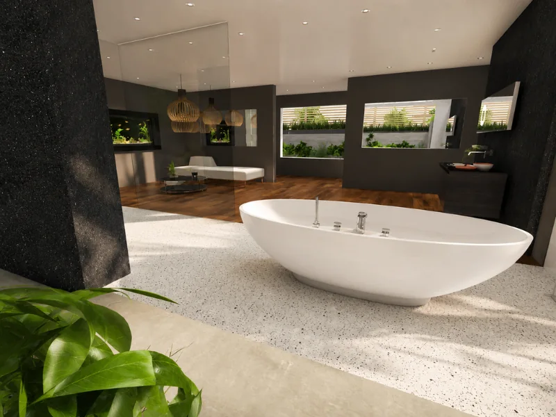 Spacious luxury bathroom with a white freestanding tub, dark charcoal walls, terrazzo flooring, warm wood accents, large mirrors, and indoor greenery.