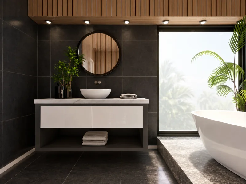 Modern bathroom with dark charcoal tiles, a floating white vanity, round mirror, wood slat accents, freestanding tub, large window, and tropical plants.