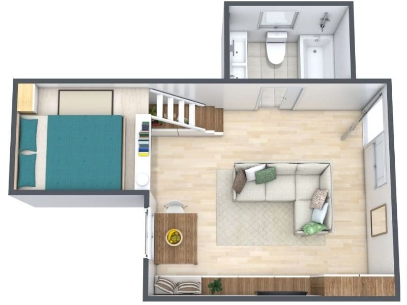 Small one-bedroom floor plan with an open living area, a compact kitchen with a small dining table, a separate bedroom, and a bathroom with a bathtub. A staircase sits between the bedroom and living space.