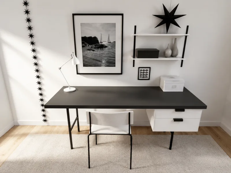 Minimalist black-and-white home office with a long black desk, white storage drawers, modern chair, wall shelves, framed coastal artwork, and star-shaped decor.