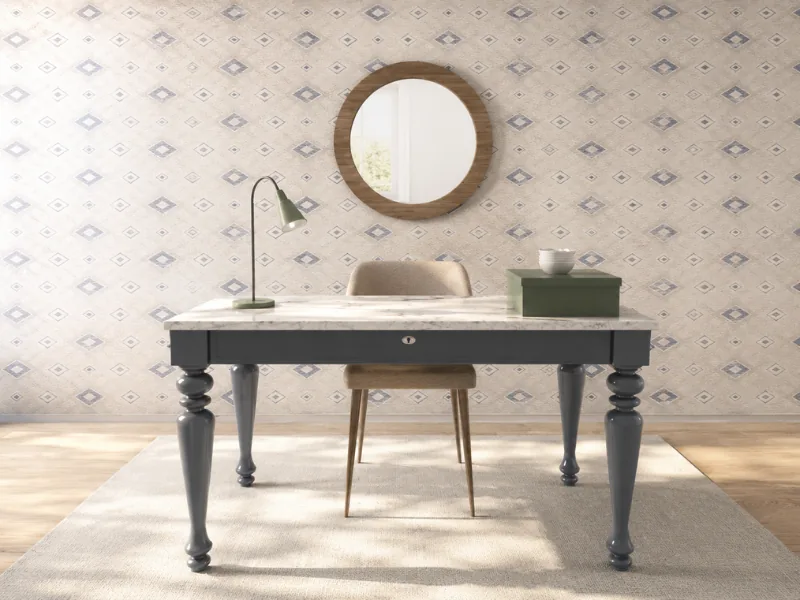 Traditional home office with a gray turned-leg desk, marble-style top, upholstered chair, round wood-framed mirror, green desk lamp, and geometric wallpaper.