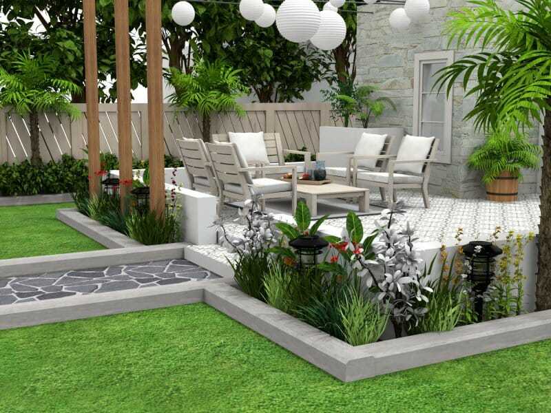 3D rendering of a cozy and stylish backyard patio with white outdoor lounge furniture arranged around a low coffee table. The elevated patio area is tiled and surrounded by lush greenery, garden beds, and decorative lanterns. String lights with round paper lanterns hang above, creating a warm and inviting atmosphere. A stone path and manicured lawn complete the garden design.