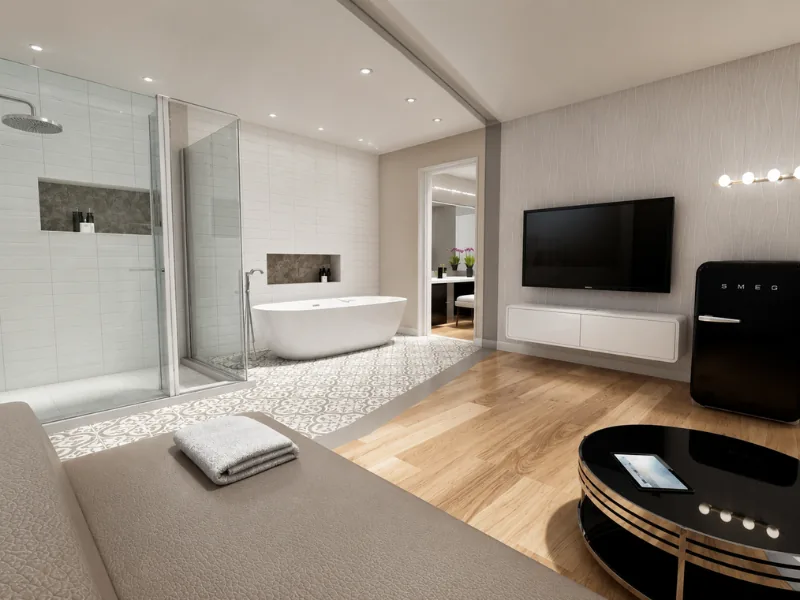 Modern open-plan bedroom with a glass-enclosed bathroom, freestanding tub, walk-in shower, patterned tile flooring, wall-mounted TV, black retro refrigerator, and wood floors.