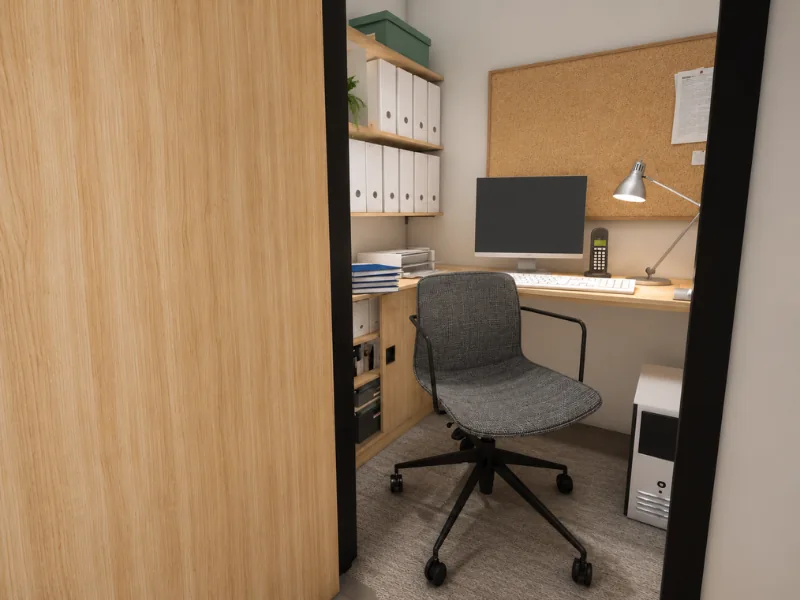 Ryan Howard’s office at Dunder Mifflin, with a compact desk, computer, rolling chair, corkboard, binders, filing cabinets, desk lamp, and office phone.