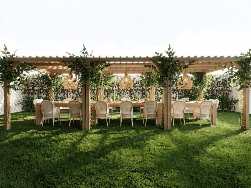 Langer gedeckter Esstisch mit Rattanstühlen unter einer begrünten Holzpergola in einem gepflegten Garten.